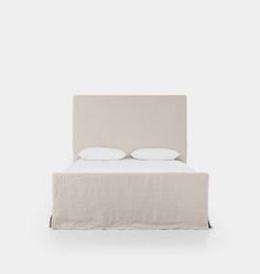 a white bed with two pillows on top of it