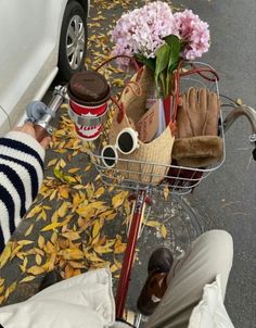 a person sitting on the ground next to a bike with flowers and other items in it