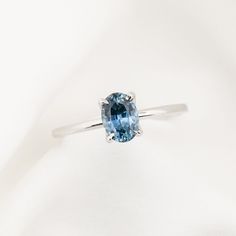 a ring with a blue stone in the center on a white background, close up