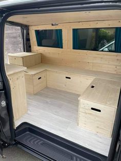 the back end of a van with wooden shelves and drawers in it's cargo area