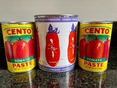 three cans of tomato paste sitting on a counter