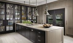 a large kitchen with lots of counter space and hanging lights over the island, along with glass cabinets