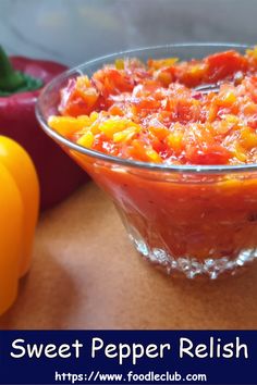 a glass bowl filled with salsa next to bell peppers