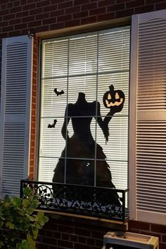 the silhouette of a woman holding a jack - o'- lantern in front of a window