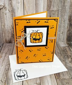 an orange halloween card with black and white pumpkins on it, tied to a wooden background