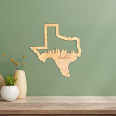 a wooden cutout of the state of texas on a wall next to a vase with flowers