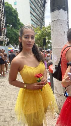 a woman in a yellow dress standing next to a pole