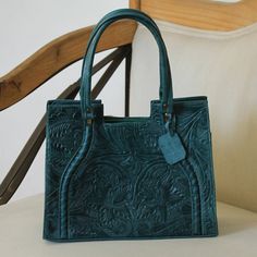 Gorgeous forest green leather embossed with a floral motif as lush as the tropics adorns this sophisticated handbag. Handcrafted by Mexican artisan Fabiola Gonzalez the handbag features a zippered pocket on the exterior and a zippered pocket plus two open pockets in the interior. The main compartment is lined with polyester and secured with a zipper. A detachable strap allows the handbag to also be worn over-the-shoulder. Imperial Leather, Favorite Purse, Unique Handbags, Embroidered Leather, Trendy Handbags, Handmade Textiles, Craft Bags, Gorgeous Bags, Bag Handle