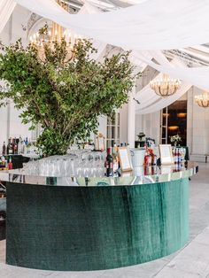 the bar is set up with wine glasses and bottles in front of an olive tree