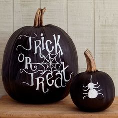 two black pumpkins with white writing on them