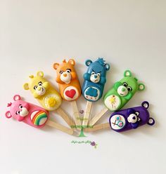 five colorful bear shaped toothbrushes sitting on top of each other in front of a white background