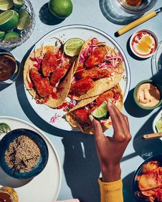 a person is reaching for some food on a plate with other plates and bowls around it