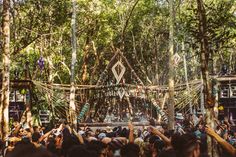 a group of people standing in front of a forest filled with trees and hanging strings