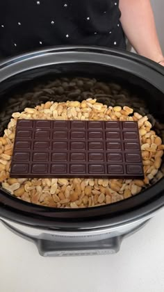 a chocolate bar sitting on top of some peanuts in an electric crockery pot