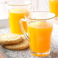 two mugs filled with orange juice and cinnamon sticks