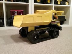 a yellow toy truck sitting on top of a floor next to shelves filled with toys