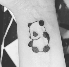 a small panda bear tattoo on the wrist