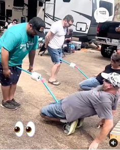 some people are doing something in front of a camper with googly eyes on it