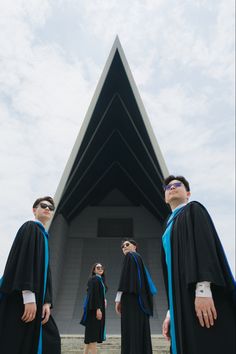 three men in graduation gowns are standing on the steps with their hands behind their backs