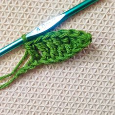 a green crochet hook is laying on a white surface