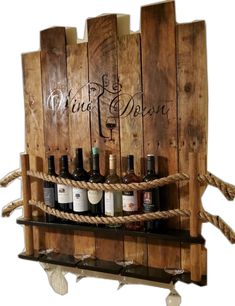 a wine rack made out of wooden pallets with rope hanging from the top and bottles on each shelf