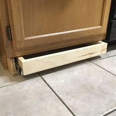 a close up of a drawer on the floor in front of a kitchen cabinet door