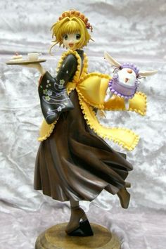 a figurine is holding a stuffed animal in her hand and wearing a yellow dress