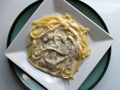 a white plate topped with pasta covered in gravy on top of a table