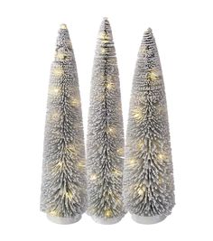 three white christmas trees with lights on them