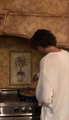 a woman in white shirt cooking food on top of an oven with the words i love you above it