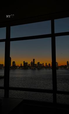 the city skyline is seen from across the water at sunset or dawn as seen through an open window