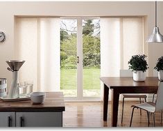 a dining room with sliding glass doors leading to an outside patio area and garden in the background