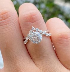 a woman's hand with a diamond ring on top of her finger and an engagement band