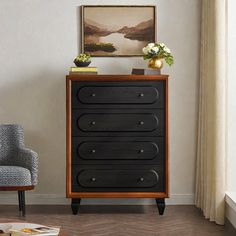 a living room with a chair and a dresser in front of a painting on the wall