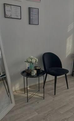 a black chair sitting next to a table on top of a hard wood floored floor