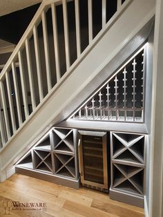 an empty wine cellar under the stairs in a room with wooden floors and white railings