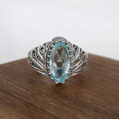 Sterling Silver Filigree Art Woman Cocktail Ring with Dazzling Blue Topaz Gemstone Artfully Abstract and Eye-Catching Our sterling silver filigree cocktail ring featuring Blue Topaz gemstone is an artistic style standout. Skilled artisans expertly shape the asymmetrical band into an avant-garde, dimensional form that boldly bucks convention. Heirloom Ring Crafted to Withstand Time The dazzling Blue Topaz takes center stage in this substantial ring, set securely within the ornate textured metalwo Fine Jewelry Blue Topaz Filigree Ring As Gift, Blue Filigree Ring Fine Jewelry Gift, Blue Topaz Filigree Rings In Fine Jewelry Style, Blue Filigree Ring As A Gift, Blue Filigree Ring As Fine Jewelry Gift, Blue Topaz Filigree Ring As Gift, Silver Filigree Ring With Blue Topaz, Silver Filigree Ring With Oval Blue Topaz, Silver Filigree Ring With Blue Topaz And Accent Stones