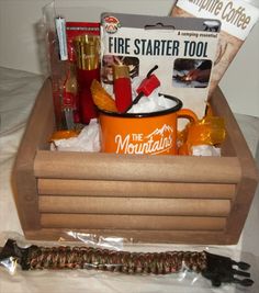 a fire starter kit sits in a wooden box on a bed with other items around it