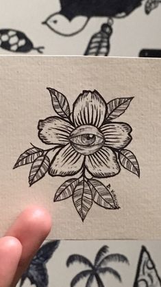 a hand holding up a piece of paper with an image of a flower on it