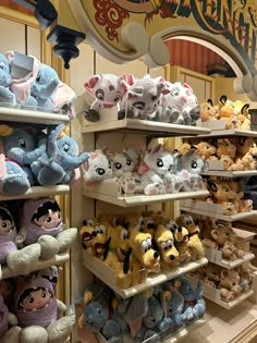 many different stuffed animals are on shelves in a store with disney's character heads hanging from the ceiling