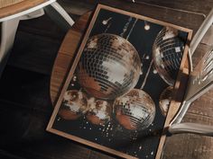 a wooden table topped with two mirrored disco ball tables next to chairs and a white chair