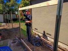 a man working on the side of a house with wood planks and tools in front of him