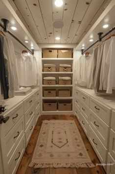 a walk in closet filled with lots of white cabinets and linens on top of drawers