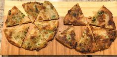 four slices of pizza sitting on top of a wooden cutting board