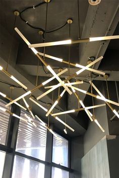 a suspended light fixture hanging from the ceiling in an empty room with lots of windows