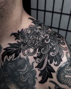 a close up of a man's chest with black and grey tattoos on it