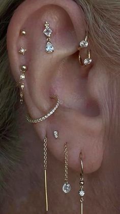 a person wearing ear piercings with chains and dangling earrings on their left side of the ear