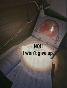 an open book sitting on top of a table next to a lamp and some papers