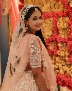 a woman in a wedding dress standing next to a flower wall