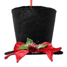 a black top hat with red ribbon and poinsettis on the side, sitting next to a candle